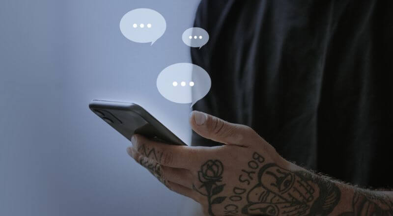 Homem com um celular na mão, e balões de conversa translúcidos saindo da tela do smartphone