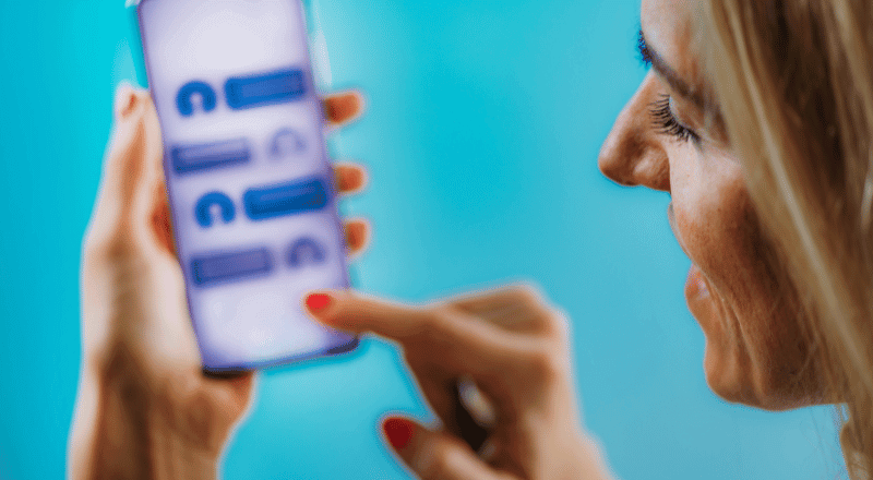 Mulher falando com um chatbot pelo celular, com semblante de satisfação